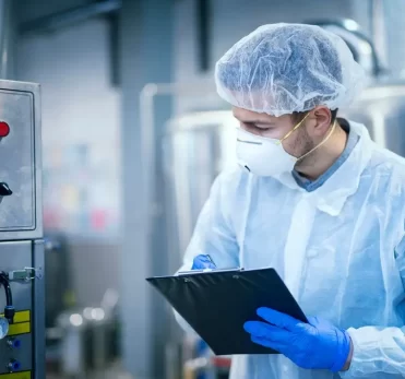 technologist-expert-protective-uniform-with-hairnet-mask-taking-parameters-from-industrial-machine-food-production-plant_342744-1176